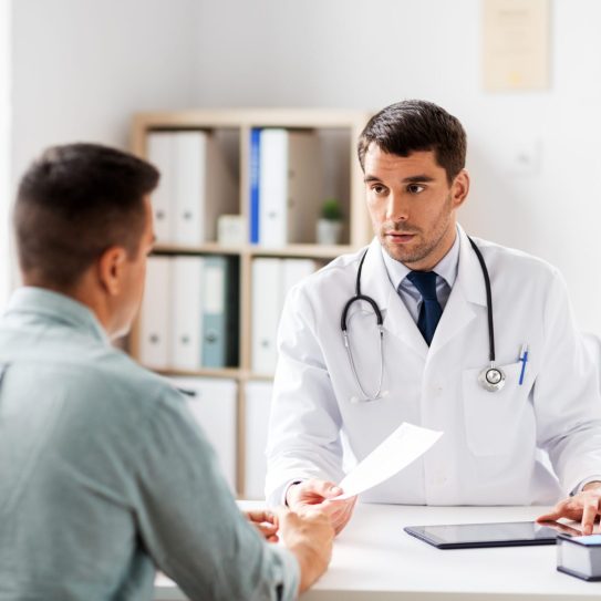 medicine, healthcare and people concept - doctor giving prescription to patient at medical office in hospital